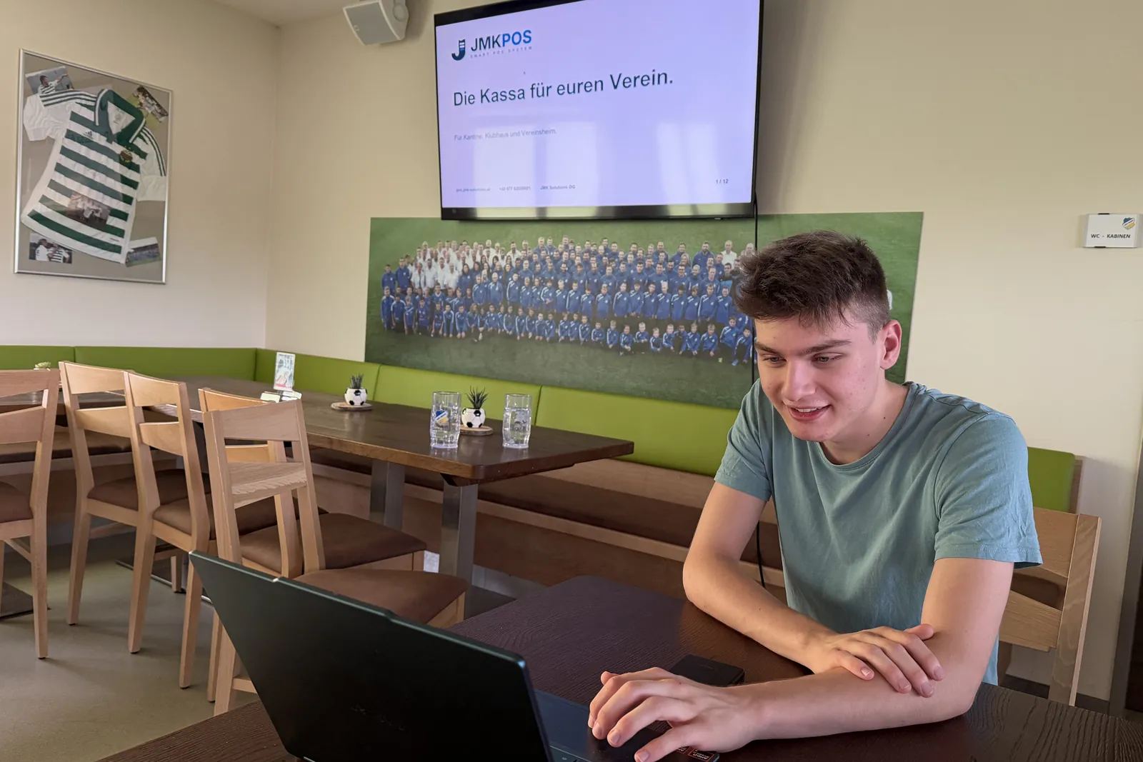Tobias Madlberger stellt JmkPOS im Vereinsheim vor, auf dem Bildschirm die Präsentation „Die Kassa für euren Verein“.